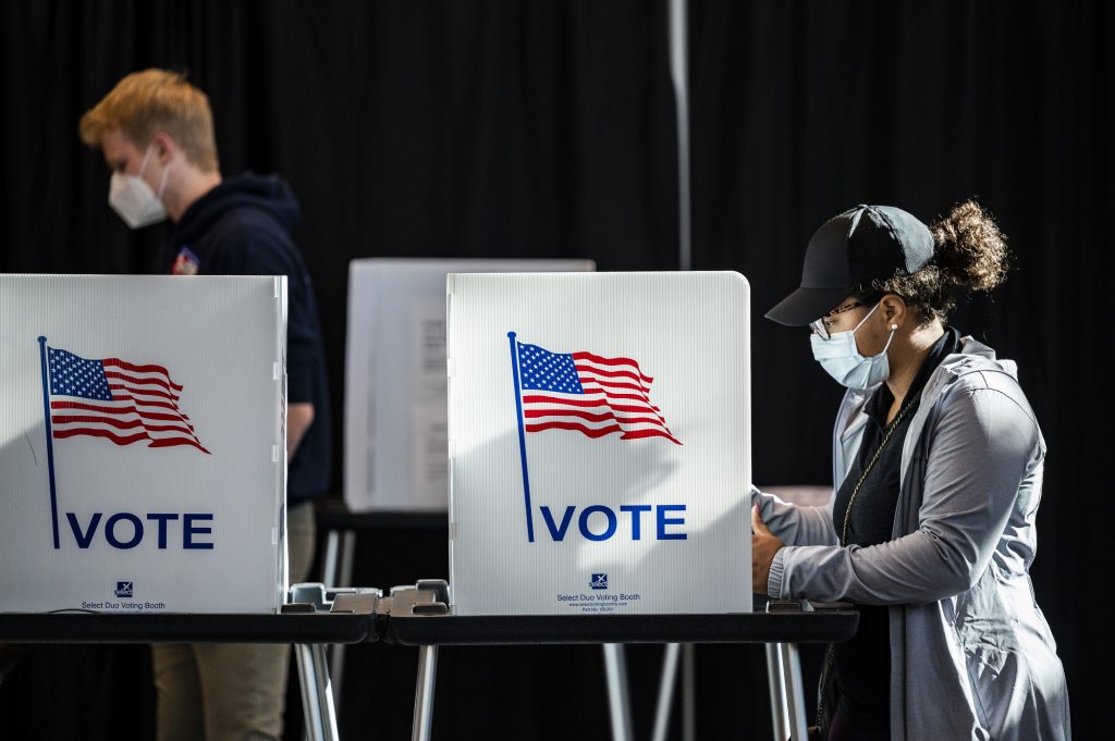 Photo of two students at voting booths casting their ballots.