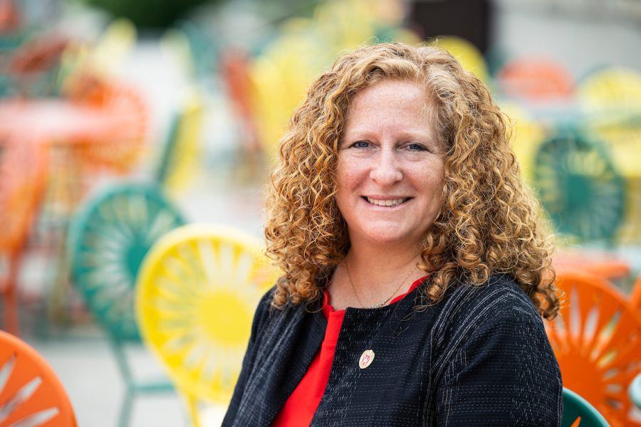 Chancellor Jennifer Mnookin seated at Memorial Union Terrace with green, yellow, and orange Terrace sunburst in background.