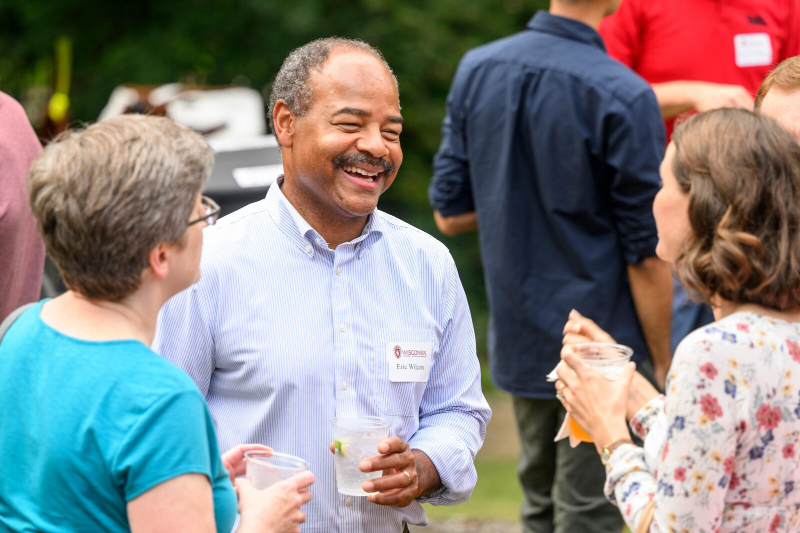 Eric Wilcots talks with two people at an outdoor gathering.